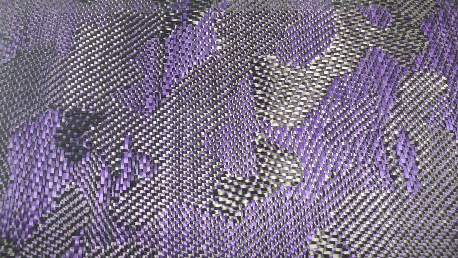 Macro shot of a high-strength purple and black carbon fiber weave.