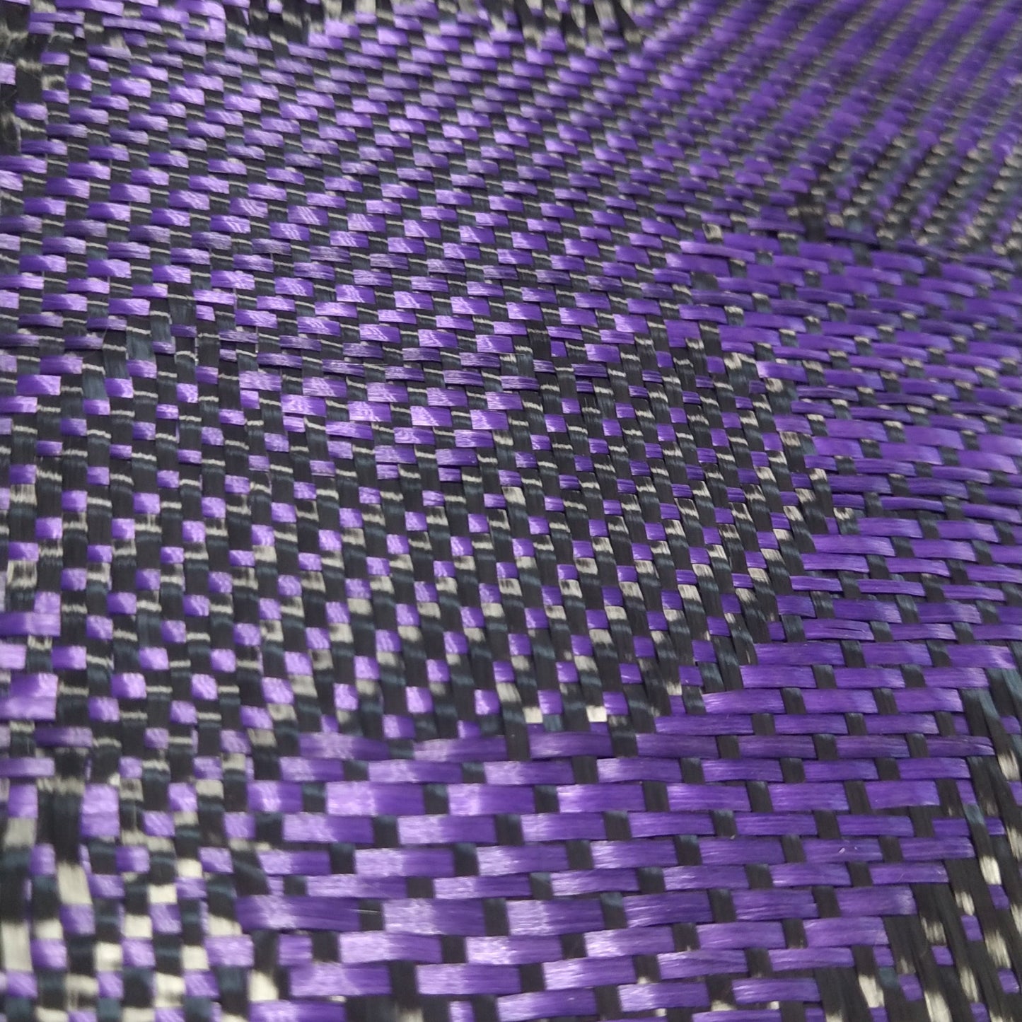 Close-up view of a purple and black carbon fiber woven fabric pattern